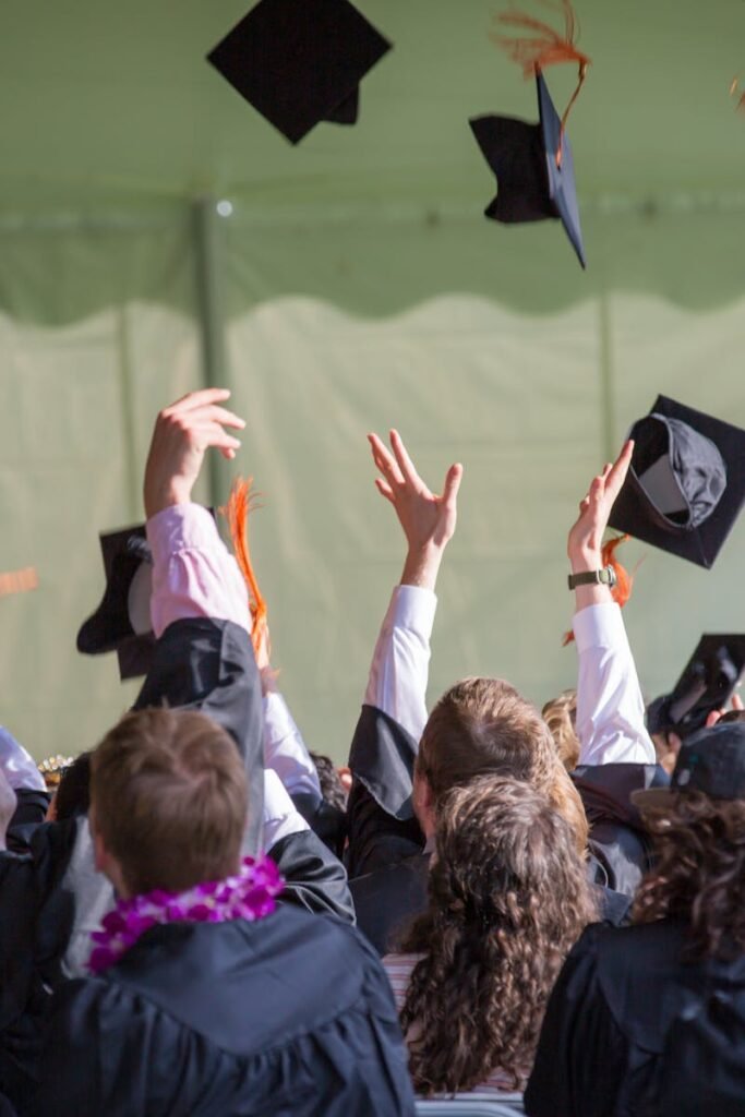 Group of graduates celebrating by tossing caps into the air during a graduation ceremony.